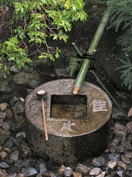 tsukubai au temple Ryoanji temple à Kyoto
The en:kanji written on the surface of the stone are without significance when read alone, but: When each is read in combination with 口 (kuchi), which the central bowl is meant to represent, the characters become 吾, 唯, 足, 知. This is read as ware tada tare o shiru and translates literally as I only know plenty (吾 = ware = I, 唯 = tada = only, 足 = tare = plenty, 知 = shiru = know).
This phrase has been translated in several ways, like
I learn only to be contented. or
I just know satisfaction. or
The knowledge that is given is sufficient.
None of those translations seems appropriate - the meaning is rather
What One Has is All One Needs. , one of the basically anti-materialistic teachings of Buddhism. The phrase would serve as a kind of mantra. Tsukubai2.JPG